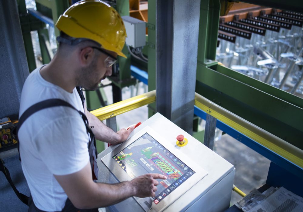 Factory worker monitoring industrial machines and production remotely in control room. Factory worker monitoring industrial machines and production remotely in control room.