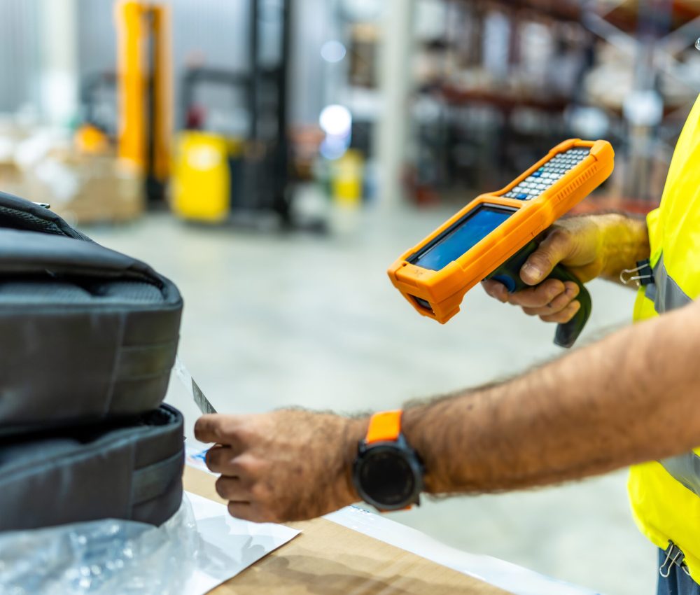 Man using scanner to read a barcode in the warehouse Close-up of the hands of a mature caucasian man uses a scanner to read the barcode of a product in the warehouse
